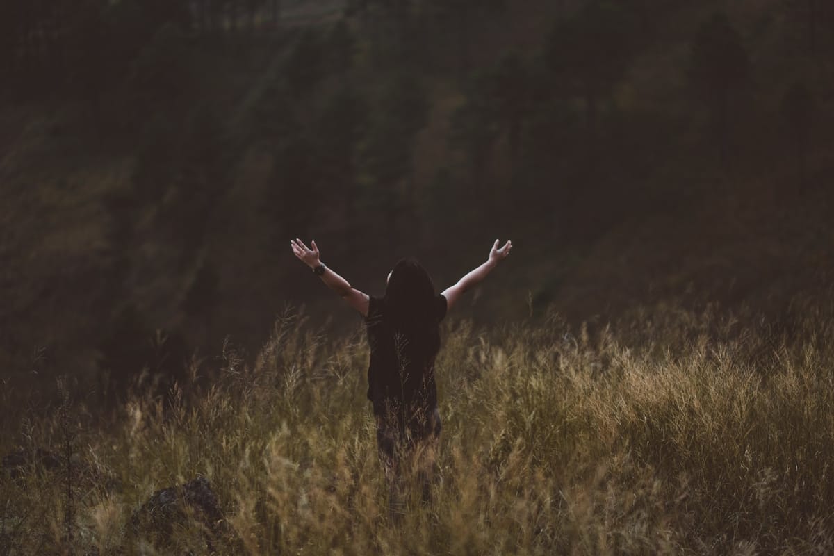 women in field with arms up