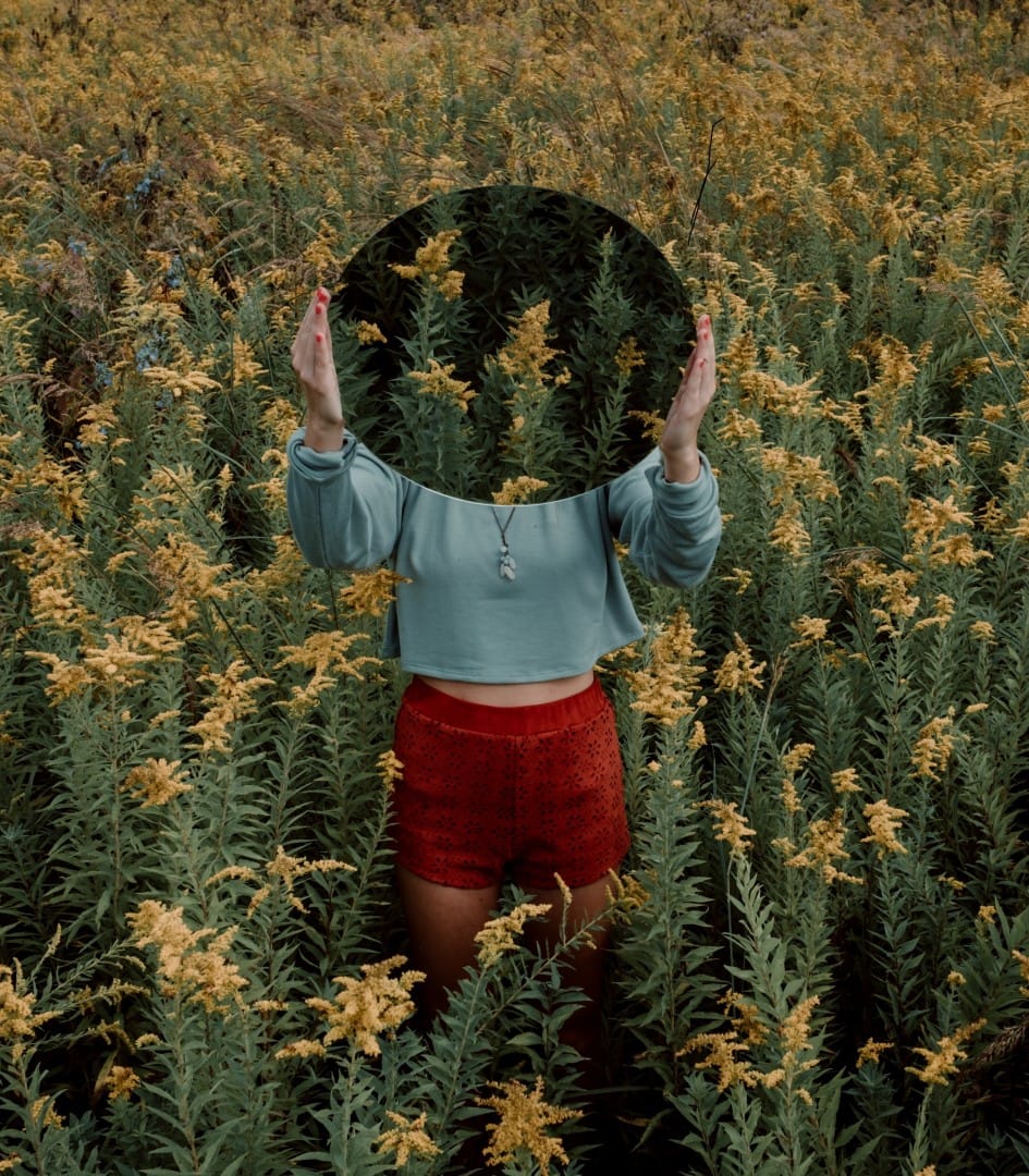 woman in field with mirror
