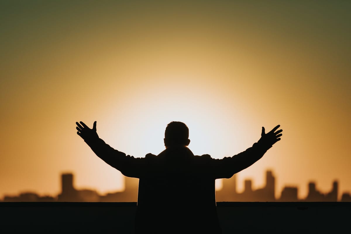 man with city scape hands up praying confidently