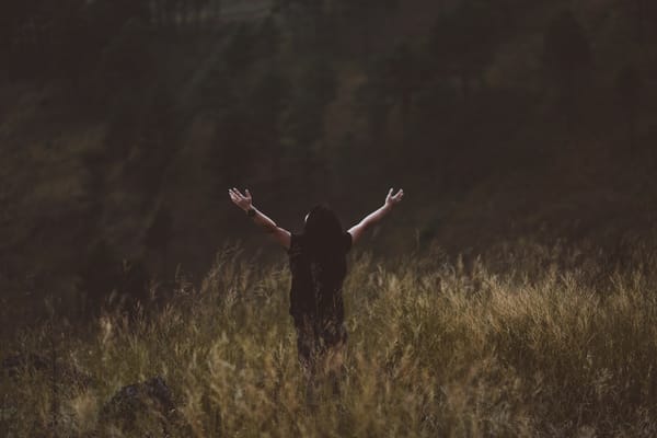 women in field with arms up