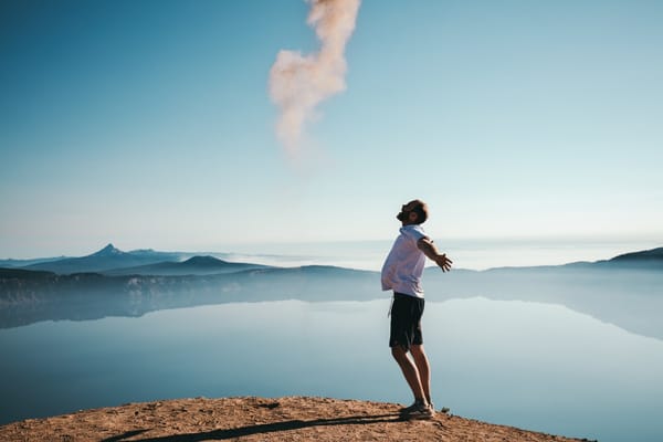 man standing above lake happy