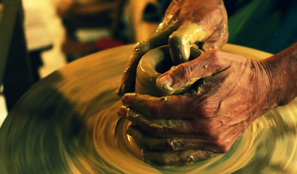 man's hands spinning pottery