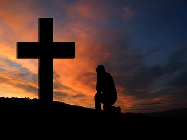 man at cross praying